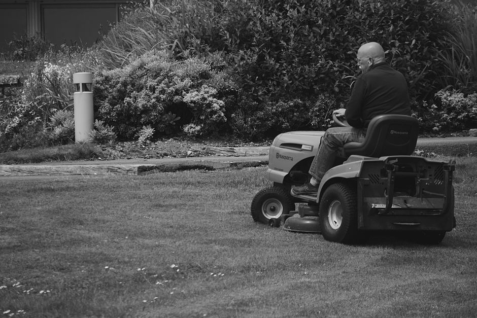 Commercial riding lawn mower cutting green grass
