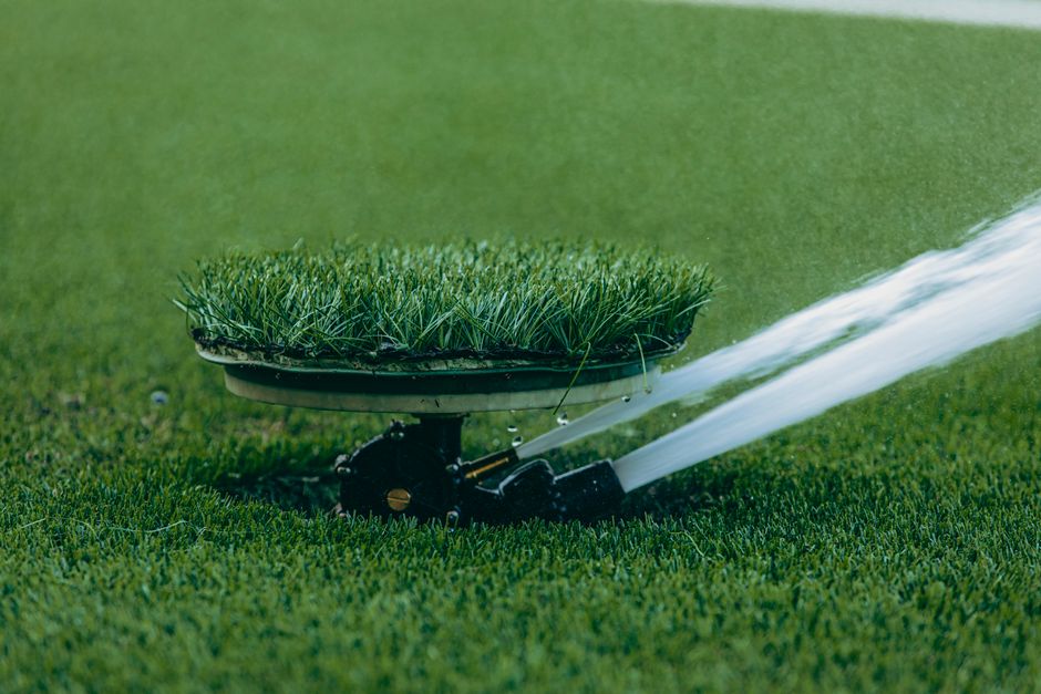 Lawn sprinkler watering green grass on a sunny day